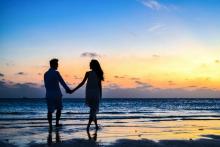 Couple on beach walking and holding hands